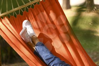 Legs of young woman resting in hammock outdoors�