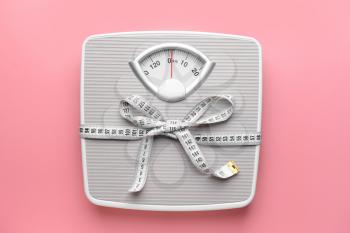 Scales and measuring tape on color background. Weight loss concept�