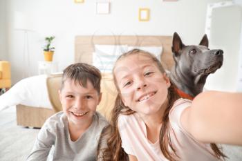 Little children with cute dog taking selfie at home�