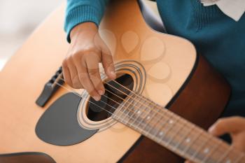 Little boy playing guitar at home, closeup�