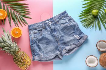 Summer composition with tropical fruits and shorts on color background�