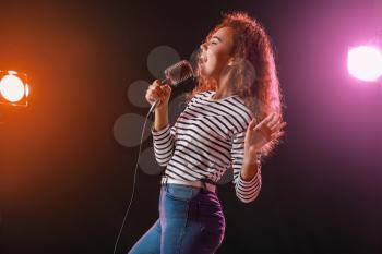 Beautiful African-American female singer with microphone on stage�