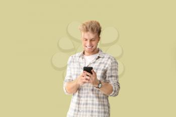 Portrait of young man with mobile phone on color background�