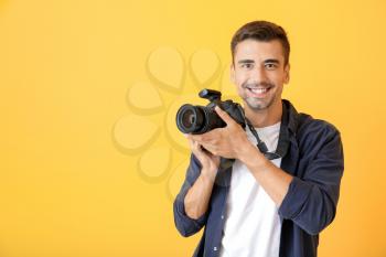 Young male photographer on color background�
