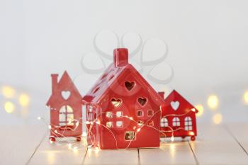 Small houses with glowing garland on white table�