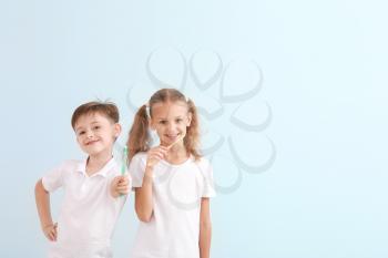 Portrait of little children brushing teeth on light background�