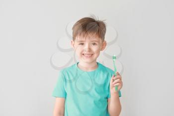 Portrait of little boy brushing teeth on light background�