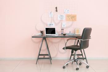 Comfortable workplace with laptop and moodboard in room�