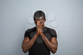 Handsome praying African-American man on grey background�
