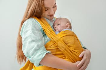 Young mother with little baby in sling on white background�