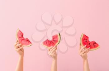 Female hands with slices of ripe watermelon on color background�