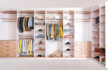 Big wardrobe with clothes in dressing room�
