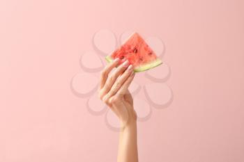 Female hand with piece of juicy watermelon on color background�