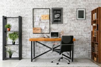 Comfortable workplace with mood board near brick wall�