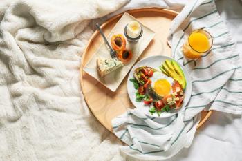Tray with tasty breakfast on bed�