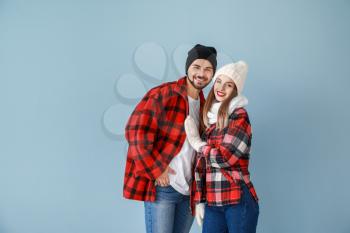 Happy young couple in warm winter clothes on color background�