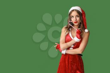 Beautiful woman dressed as Santa on color background�