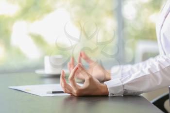 Young businesswoman meditating at workplace in office�