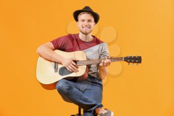 Handsome man playing guitar on color background�