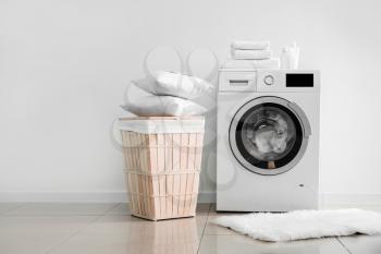 Modern washing machine with laundry near light wall�