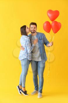 Portrait of beautiful young couple with air balloons on color background�
