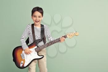 Little boy playing guitar on color background�