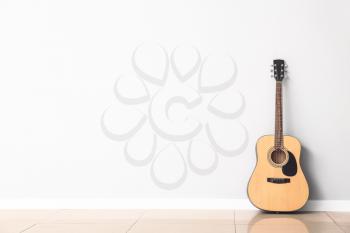 Modern acoustic guitar near white wall�