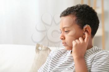 Little African-American boy with hearing aid at home�