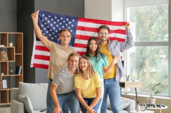 Happy young friends with national flag of USA at home�