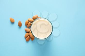 Glass of tasty almond milk on color background�