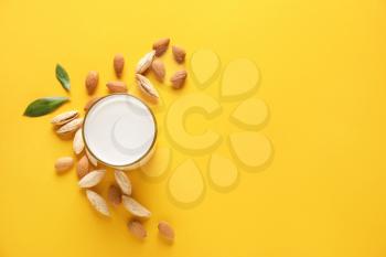 Glass of tasty almond milk on color background�