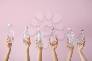 Female hands with bottles of water on color background�