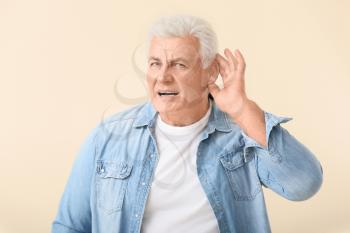 Mature man with hearing problem on light background�