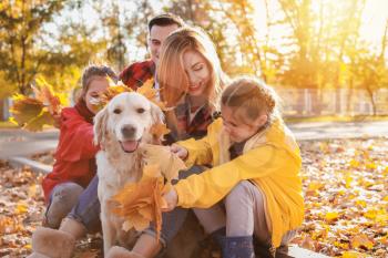 Happy family with dog resting in autumn park�