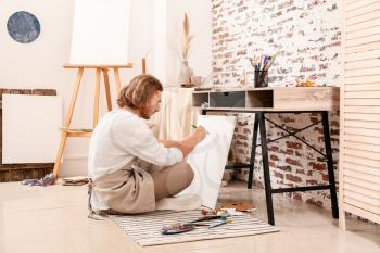 Young male artist painting at home�