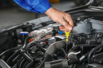 Male mechanic checking level of oil in car engine�