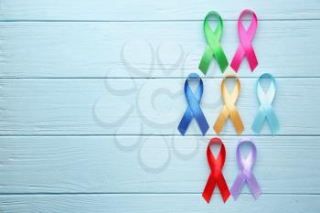 Different awareness ribbons on color wooden background�