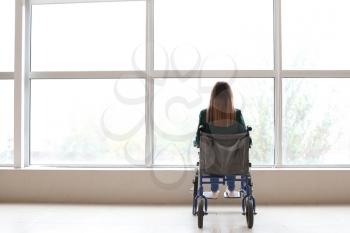 Handicapped young woman in wheelchair near window�