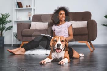 Beautiful African-American woman with cute dog at home�