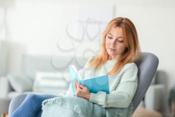 Beautiful mature woman reading book at home�