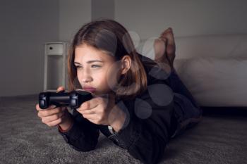 Teenage girl playing video game late in evening�