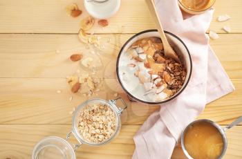 Tasty granola with yogurt in bowl on wooden table�
