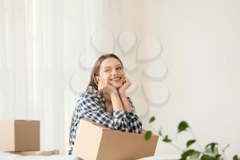 Happy young woman with moving box in new house�