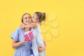 Little girl greeting her mother on color background�
