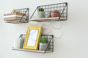 Shelves with decor hanging on light wall�