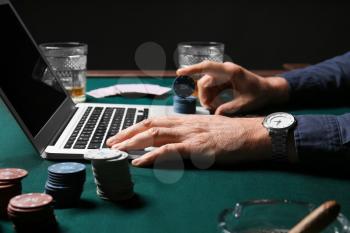 Mature businessman playing poker online, closeup�