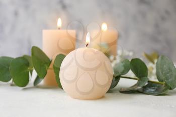 Glowing candles with eucalyptus on white background�