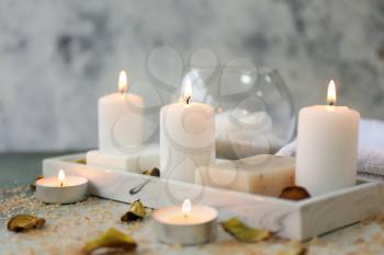 Glowing candles with soap on table�