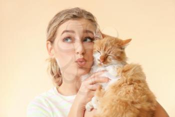 Beautiful young woman with cute cat on color background�