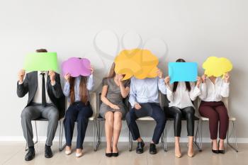 Group of business people with blank speech bubbles near light wall�